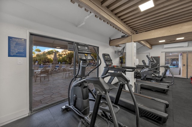 exercise room with a wall mounted air conditioner, baseboards, and vaulted ceiling