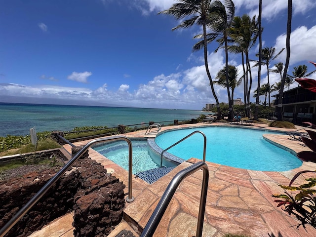 view of pool with a pool with connected hot tub, a water view, and a patio area