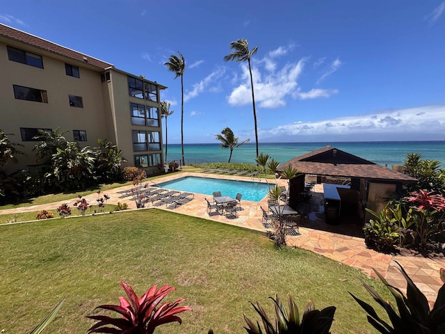 view of swimming pool featuring a patio, a yard, and a water view