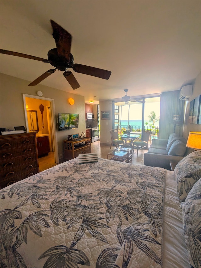 bedroom with an AC wall unit, expansive windows, ceiling fan, ensuite bathroom, and light tile patterned floors