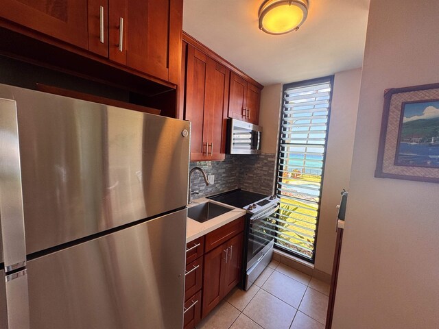 kitchen featuring light countertops, tasteful backsplash, a sink, light tile patterned flooring, and appliances with stainless steel finishes