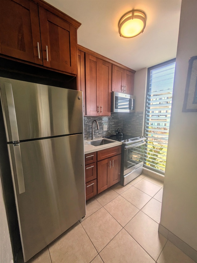 kitchen with light tile patterned floors, sink, stainless steel appliances, and decorative backsplash