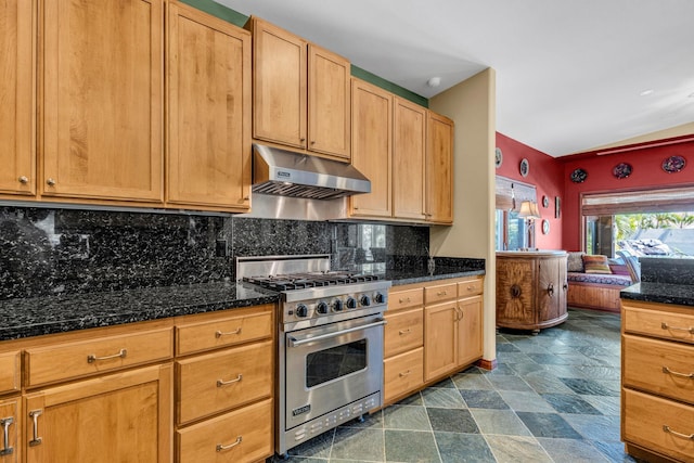 kitchen with under cabinet range hood, dark stone countertops, backsplash, designer stove, and stone finish flooring