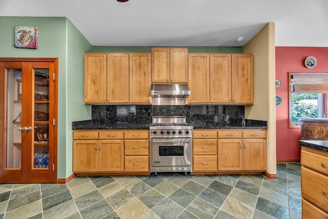 kitchen with premium stove, baseboards, decorative backsplash, stone finish floor, and under cabinet range hood