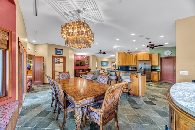 dining area featuring recessed lighting, stone finish floor, and ceiling fan with notable chandelier