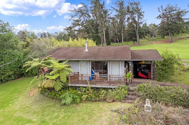 back of property with roof with shingles, a lawn, and a deck