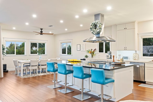 kitchen with white cabinets, appliances with stainless steel finishes, a center island, and island range hood