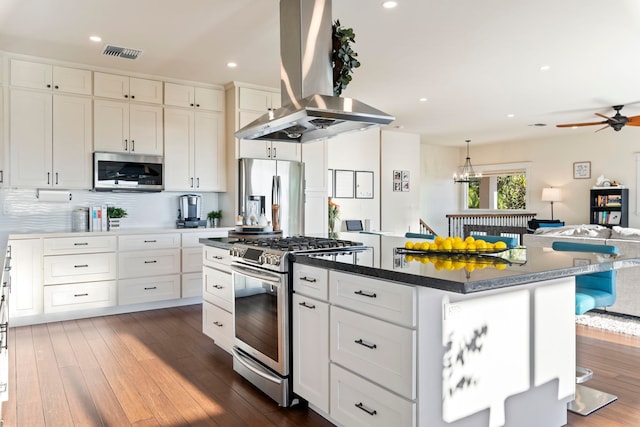 kitchen featuring a center island, white cabinetry, appliances with stainless steel finishes, a breakfast bar area, and island range hood