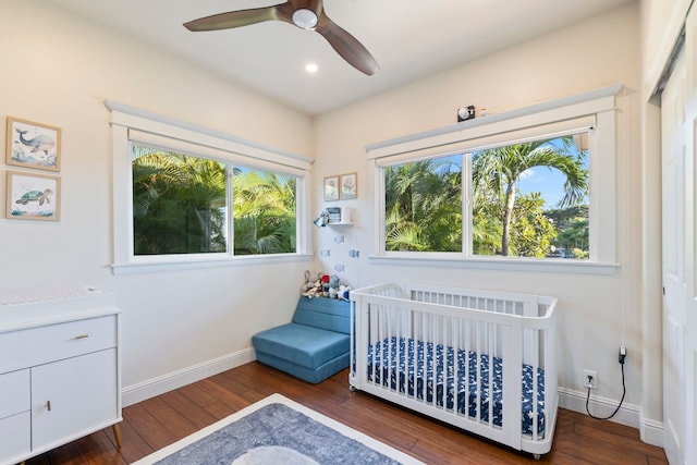 bedroom featuring ceiling fan, dark hardwood / wood-style floors, a nursery area, and a closet