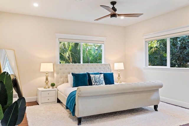 bedroom featuring ceiling fan, wood-type flooring, and multiple windows