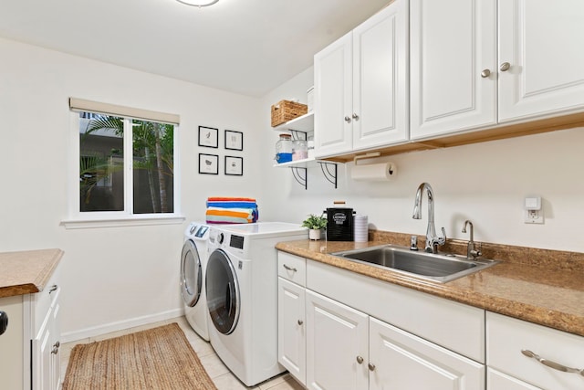 washroom with light tile patterned floors, sink, washer and clothes dryer, and cabinets