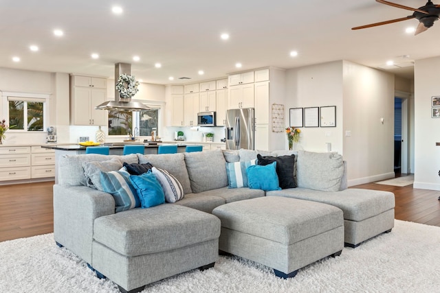 living room with ceiling fan, light wood-type flooring, and sink