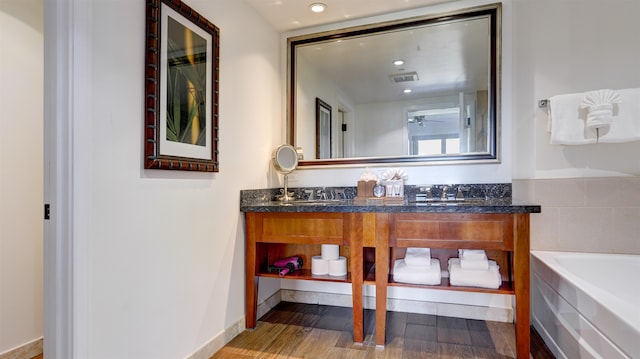 bathroom featuring hardwood / wood-style floors, vanity, and a tub to relax in