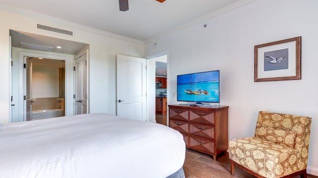 bedroom featuring hardwood / wood-style floors, ensuite bath, ceiling fan, and crown molding