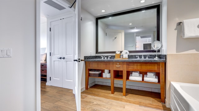 bathroom featuring a bath, hardwood / wood-style flooring, and vanity