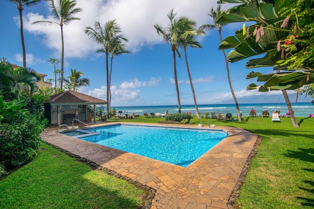 view of swimming pool with a yard, a water view, and an outdoor structure