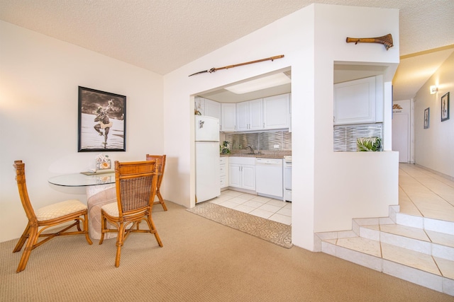 tiled dining room featuring a textured ceiling, vaulted ceiling, and sink