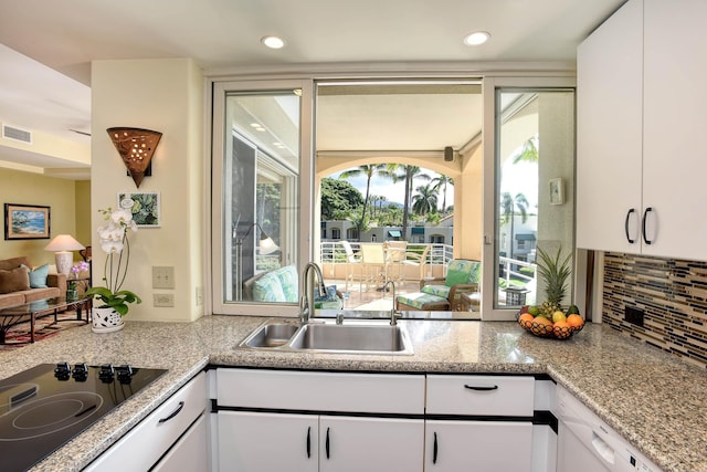 kitchen with white cabinets, decorative backsplash, stovetop, and sink