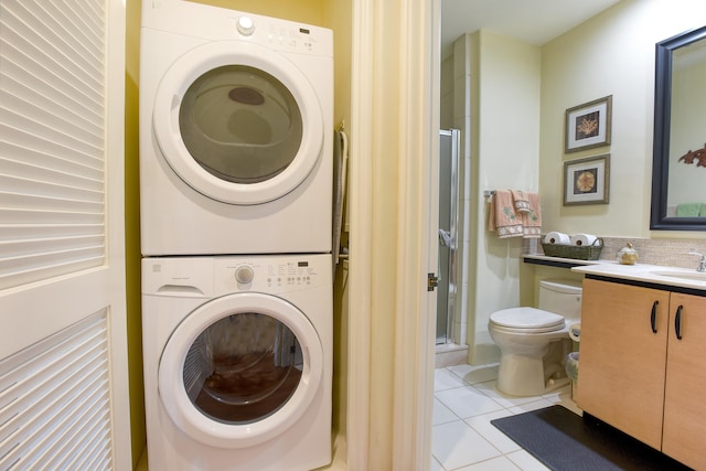 washroom with sink, light tile patterned floors, and stacked washer and dryer