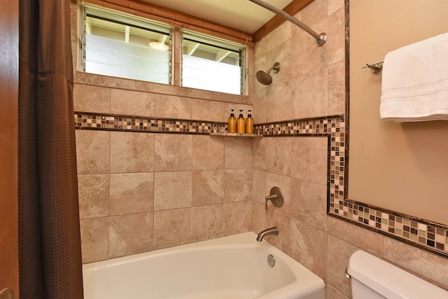 bathroom featuring shower / tub combo, toilet, and tile walls