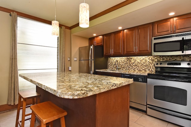 kitchen with appliances with stainless steel finishes, tasteful backsplash, light tile floors, light stone countertops, and hanging light fixtures