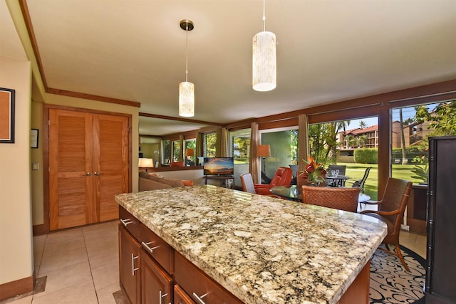 kitchen with hanging light fixtures, light stone countertops, a center island, and light tile floors