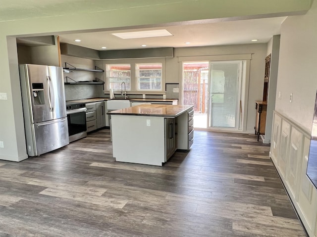 kitchen with open shelves, a kitchen island, dark wood-type flooring, stainless steel appliances, and a sink