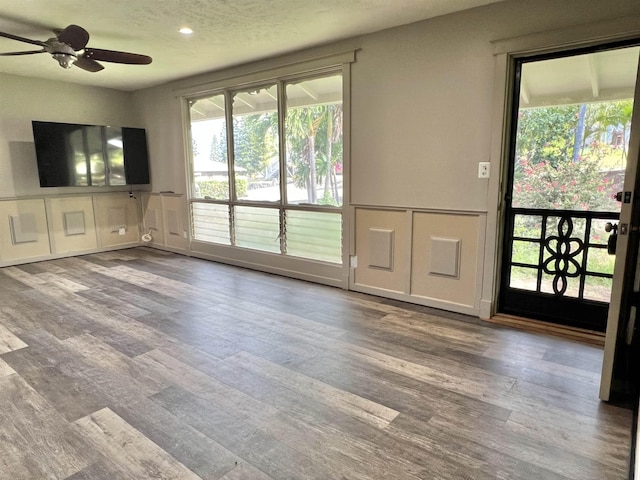 unfurnished living room with wood finished floors, a decorative wall, and a ceiling fan