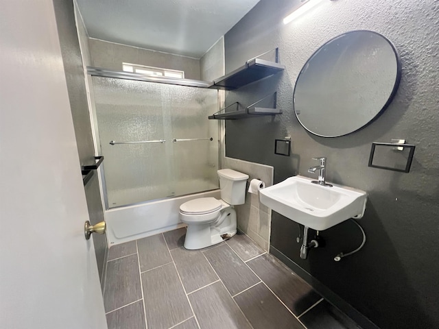 bathroom featuring a sink, toilet, combined bath / shower with glass door, and wood tiled floor