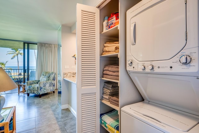 washroom featuring a water view, tile floors, and stacked washer / drying machine