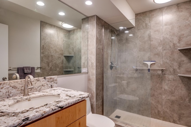 bathroom featuring large vanity, toilet, and a tile shower