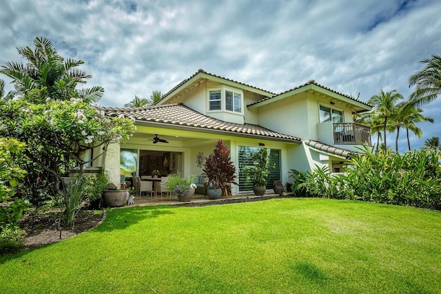 back of property with a yard, a balcony, ceiling fan, and a patio area