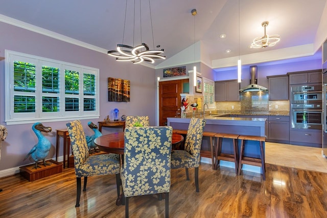 dining room featuring lofted ceiling, sink, wood-type flooring, crown molding, and a chandelier