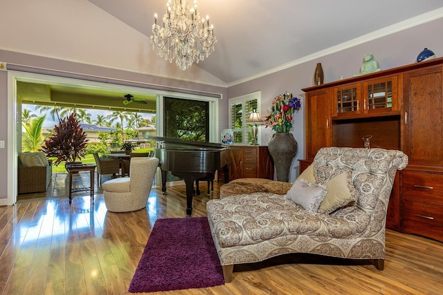 living area featuring vaulted ceiling, crown molding, a chandelier, and light hardwood / wood-style flooring