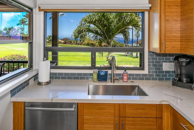 kitchen with tasteful backsplash, dishwasher, sink, and light stone countertops