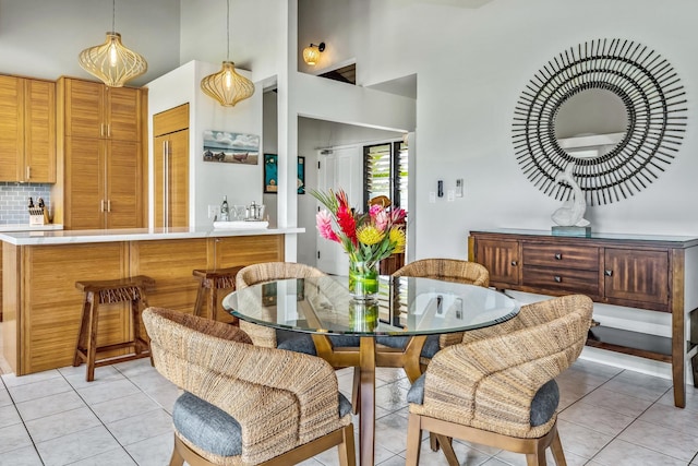 tiled dining space featuring a towering ceiling