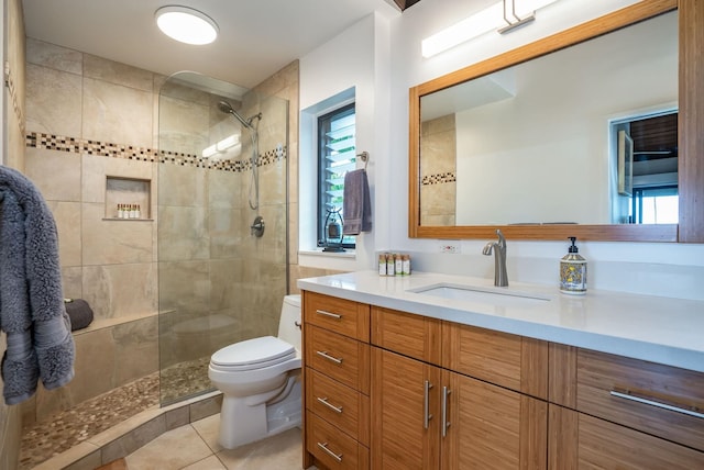 bathroom with tile patterned flooring, vanity, toilet, and a tile shower