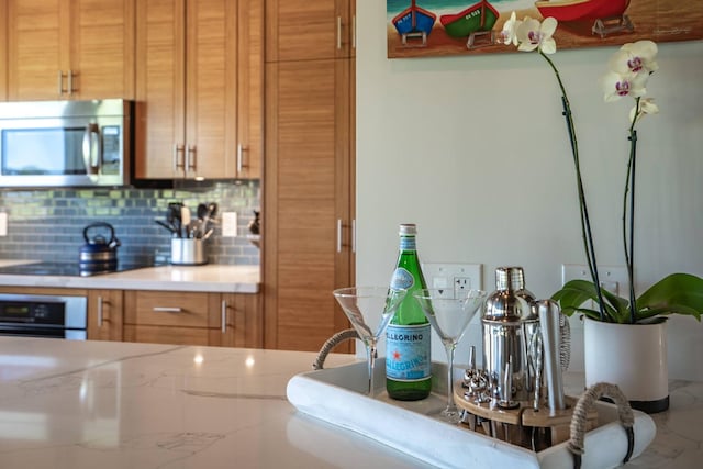 10 Wailea Ekolu Pl Unit 1204, Kihei, HI 96753 - kitchen featuring appliances with stainless steel finishes, tasteful backsplash, light countertops, and brown cabinets
