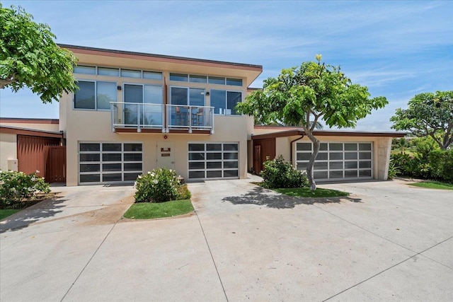 209 Holokahiki Ln Unit 103, Kihei, HI 96753 - view of front of home with fence, concrete driveway, a balcony, an attached garage, and stucco siding