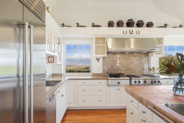 kitchen with wall chimney exhaust hood, stainless steel appliances, butcher block countertops, light hardwood / wood-style floors, and white cabinets