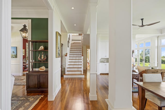 hall with hardwood / wood-style flooring, ornate columns, and ornamental molding