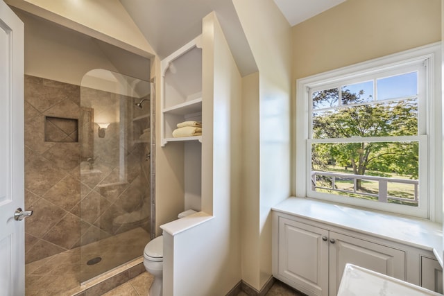 bathroom with a tile shower and toilet