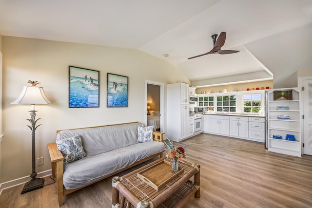 living room featuring light hardwood / wood-style floors, ceiling fan, lofted ceiling, and sink