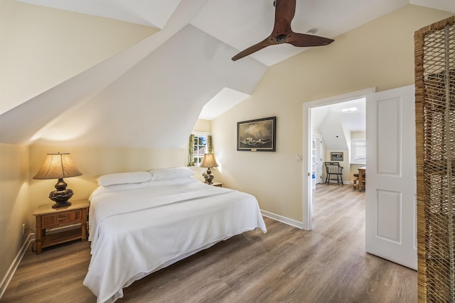 bedroom with hardwood / wood-style floors, ceiling fan, multiple windows, and vaulted ceiling