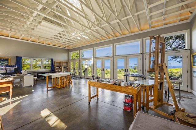 interior space with french doors, a towering ceiling, and a workshop area