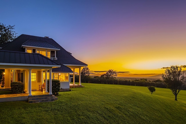 back house at dusk featuring a yard