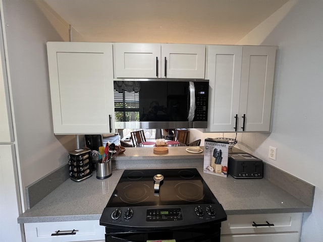 kitchen featuring white cabinets and black stove