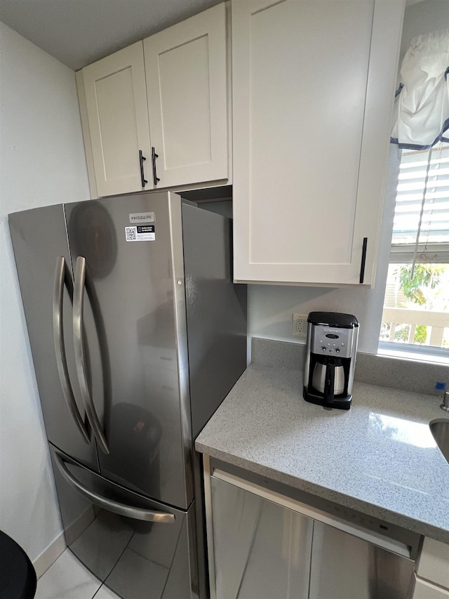 kitchen with white cabinetry, light tile patterned floors, light stone countertops, and appliances with stainless steel finishes