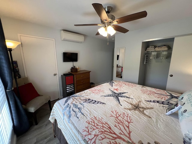 bedroom featuring a wall mounted air conditioner, ceiling fan, wood-type flooring, and a closet