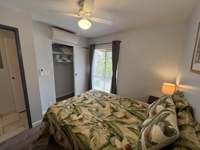 bedroom with a closet, a wall mounted AC, ceiling fan, and dark hardwood / wood-style flooring